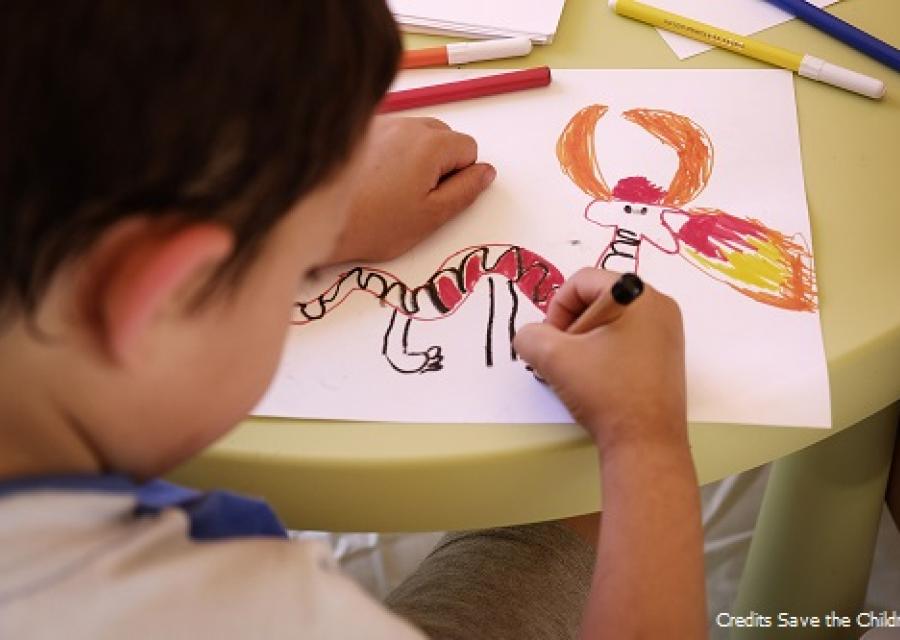 bambino di spalle che disegna un drago