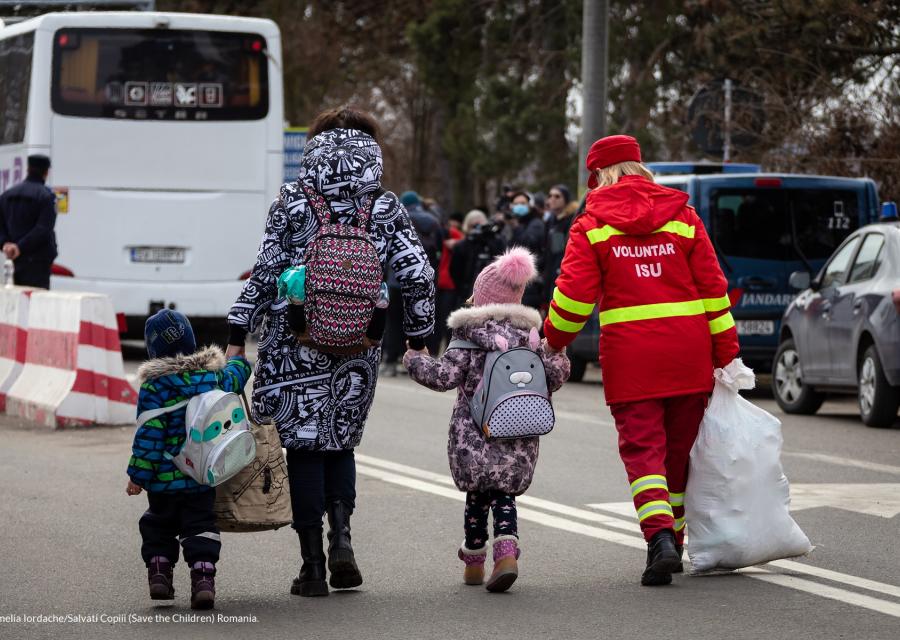 una famiglia di persone cammina in strada e è ripresa di spalle. Sono un uomo una donna e due bambini.