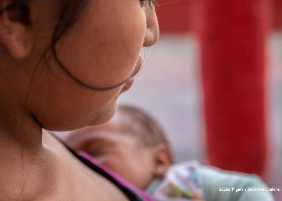Inquadratura di una parte del volto di una donna, focalizzato sulla guancia per non farla riconoscere. Sullo sfondo il viso di un neonato