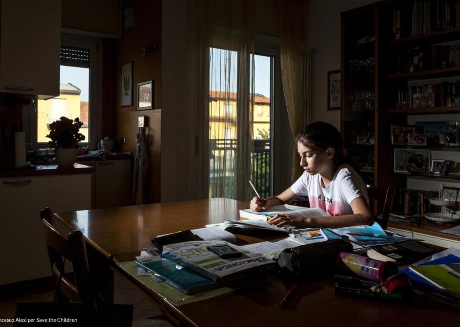 Immagine di una bambina impegnata a studiare in una stanza buia