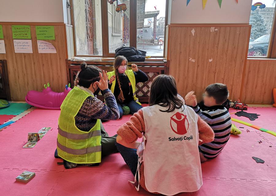 operatori save the children giocano a terra insieme a un bambino su un pavimento colorato di rosa