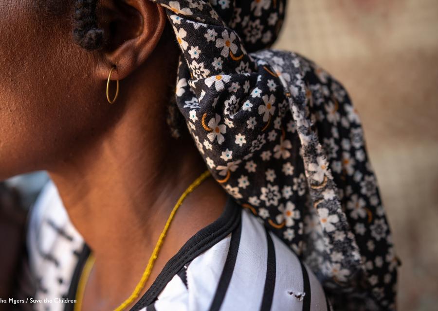 profilo di donna con fascia colorata sul capo, orecchino e collana color ora, indossa una maglietta a righe bianca e nera