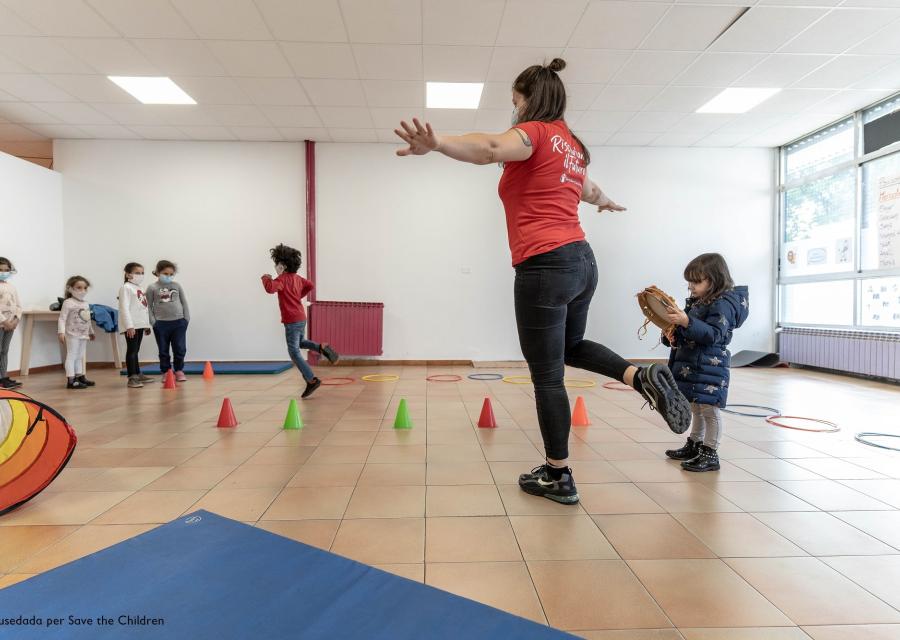 operatrice save the children gioca con alcuni bambini e bambine piccoli in uno spazio mamme