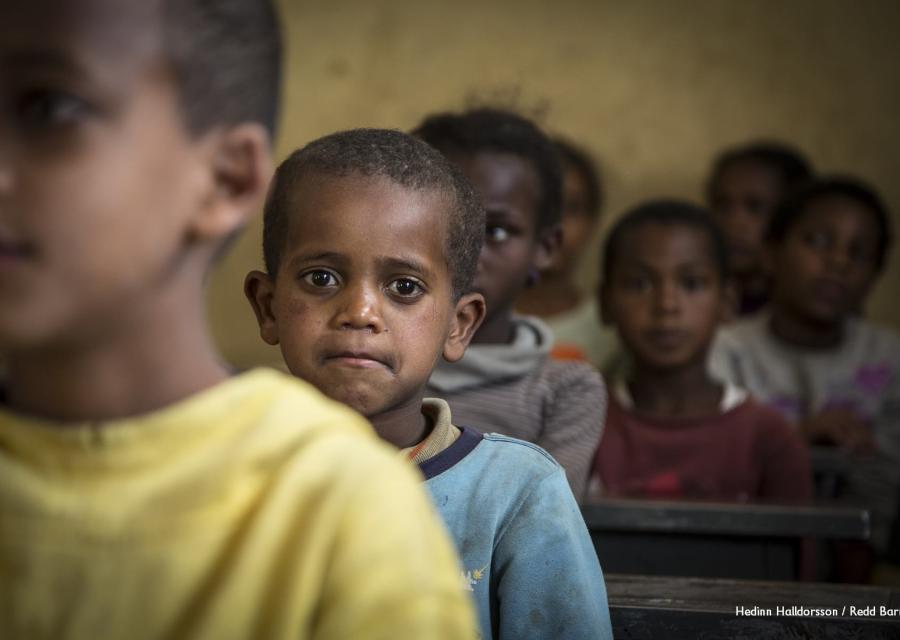 Primo piano di un bambino etiope con maglietta azzura che compare dietro al viso di un altor bambino davanti a lui che si vede sfocato