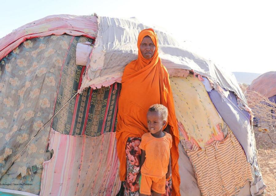 bambina etiope abbracciata dalla mamma in piedi di fronte la loro tenda nel campo per sfollati interni in Somalia