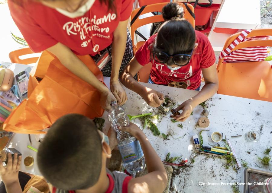 Due bambini giocano con erbe su un tavolo ripresi dall alto