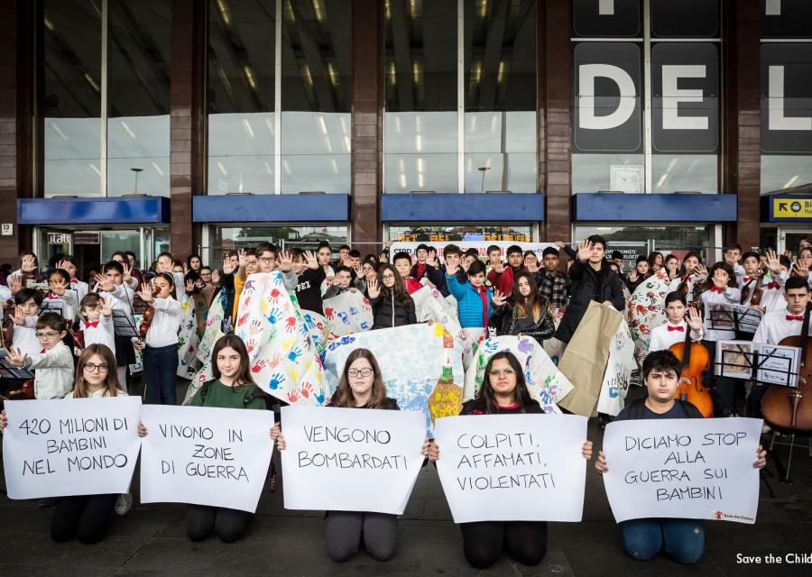 Bambini tengono in mano cartelli per flash mob alla Stazione Roma Termini