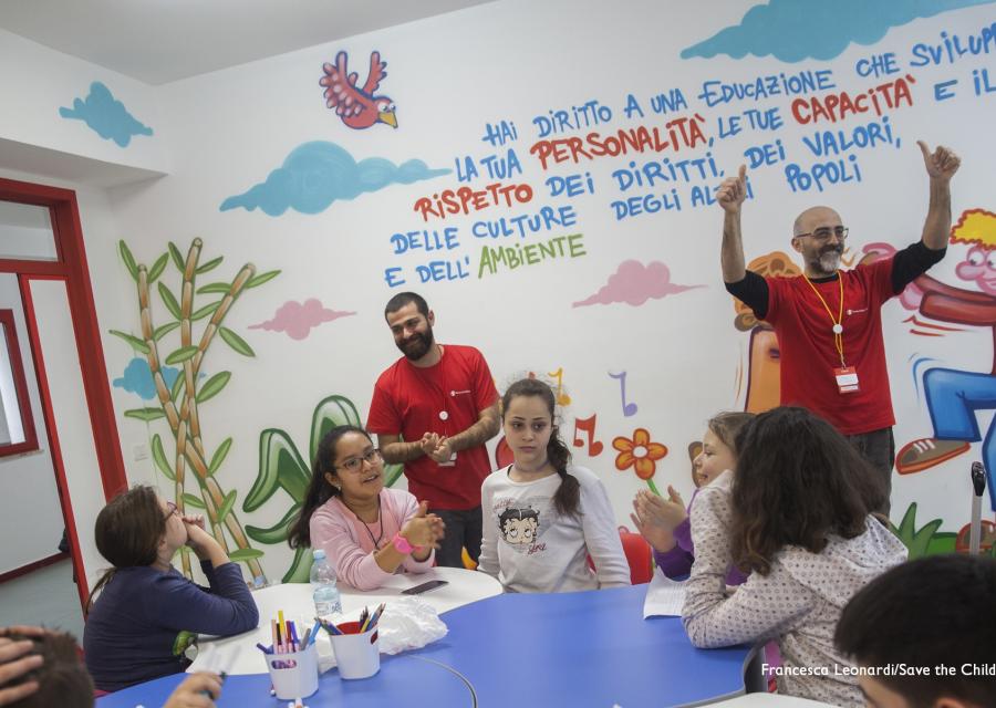 Bambini e operatori Save the Children intorno a un tavolo