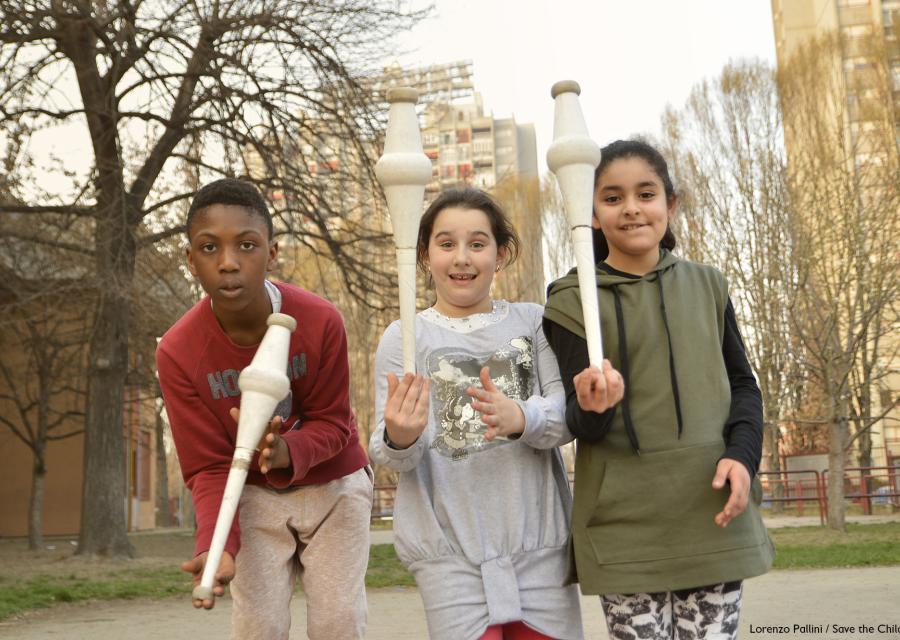 foto all aperto di 3 bambini con birilli in mano che giocano