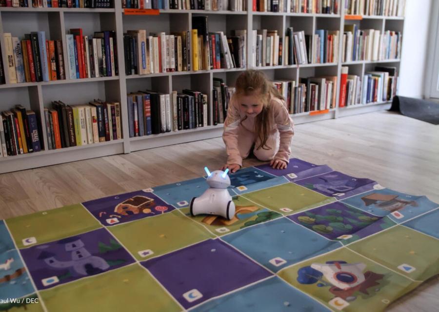 gioco stem per bambina che gioca con robot su un tappeto 