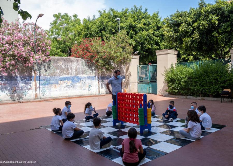 Bambini seduti a terra che ascoltano il maestro