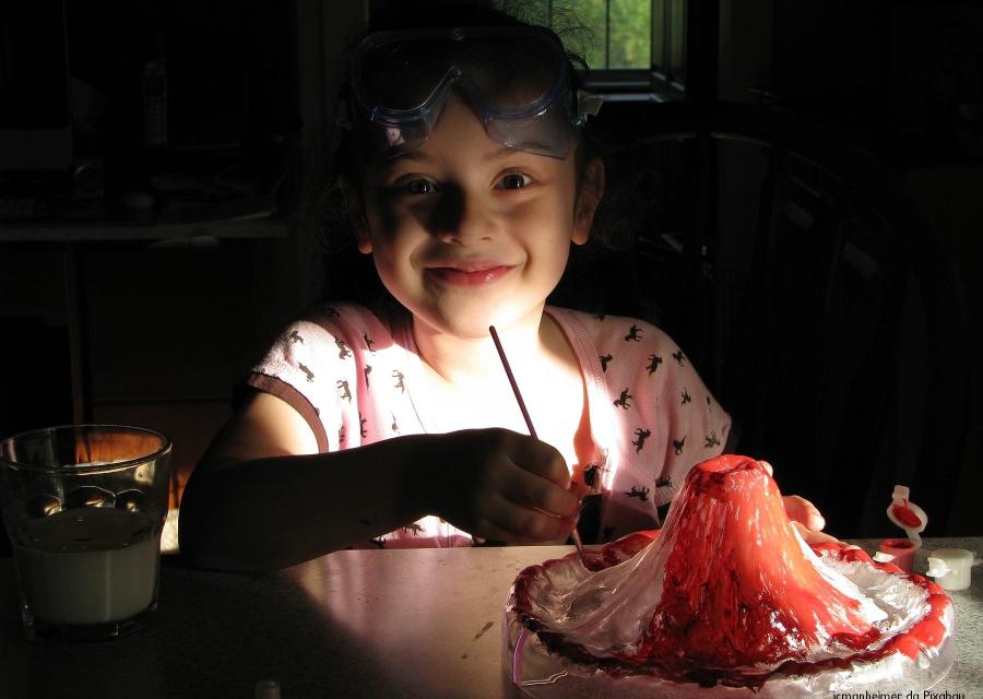 bambina sorridente con maschera snorkeling sulla fronte seduta al tavolo tiene in mano un pennello mentre lavora a un esperimento