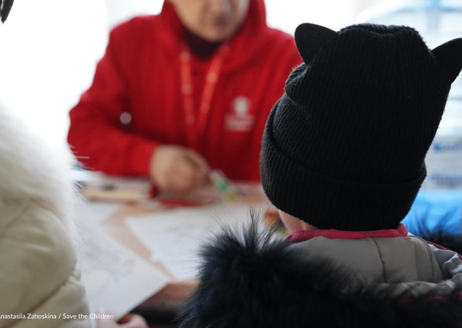 Bambino con operatore Save the Children che leggono un libro 