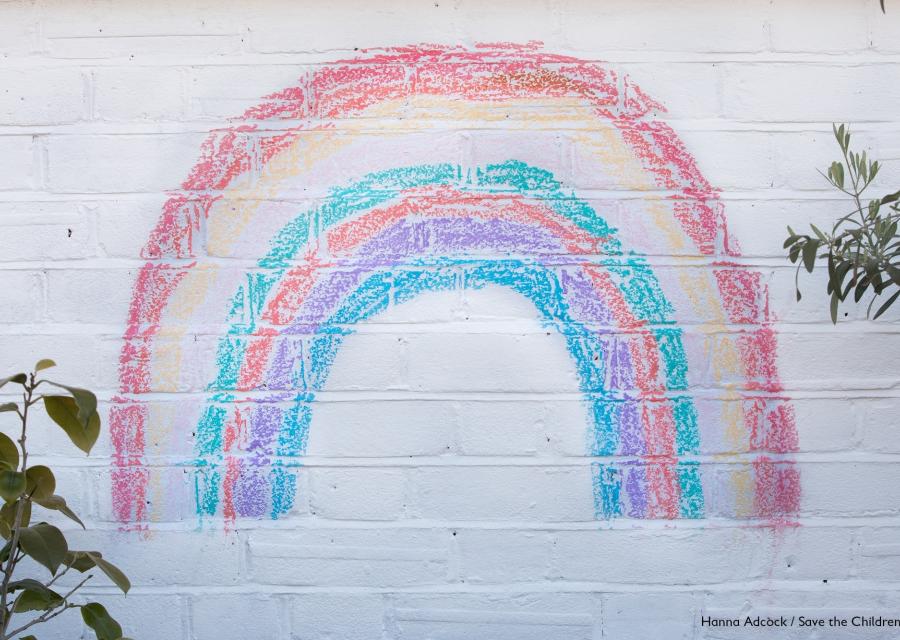 arcobaleno fatto con gessetti colorati su muro bianco