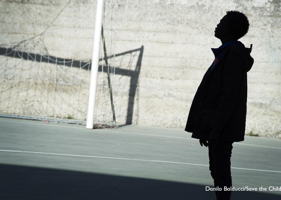 Sagoma nera di un bambino migrante in un campo di calcio