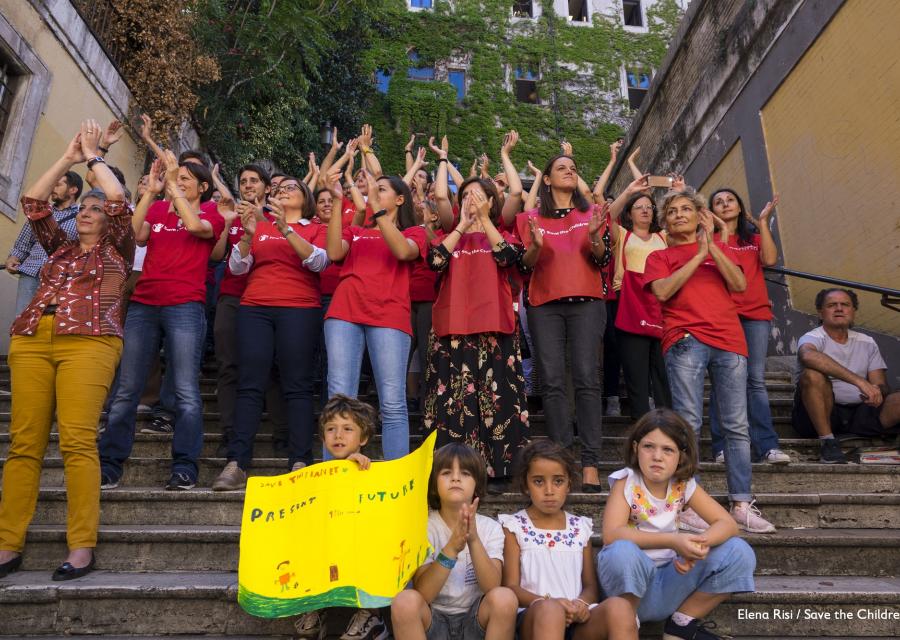 staff di save the children Italia applaude ai ragazzi che manifestano per il Global Strike fo Future, insieme a loro 4 bambini che applaudono sorridenti.