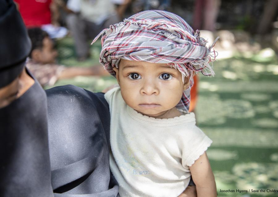 bambino dello yemen con kefiah in testa in braccio alla mamma 