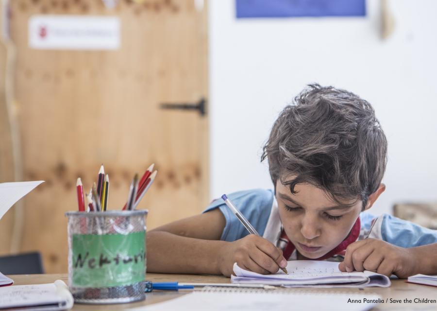 Bambino siriano fa i compiti al banco di scuola
