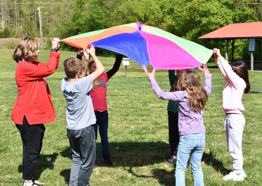 bambini giocano in cerchio con un telo colorato