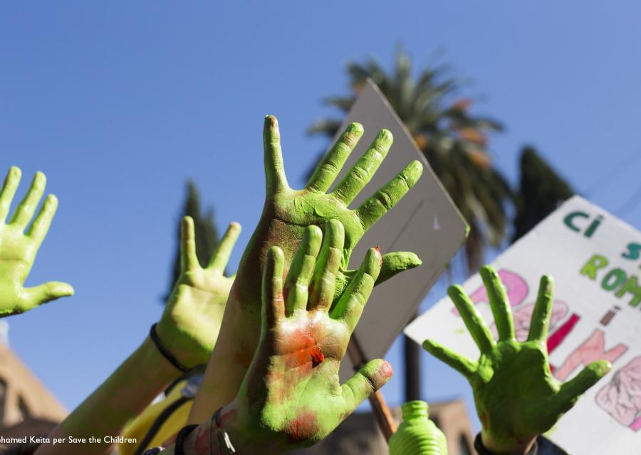 mani colorate di verde che si alzano verso il cielo durante una manifestazione per l'ambiente