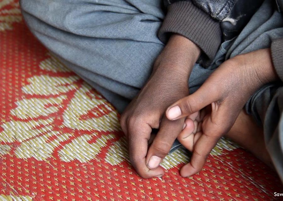 primo piano di mani di un bambino seduto a terra a gambe incrociate su un tappetino