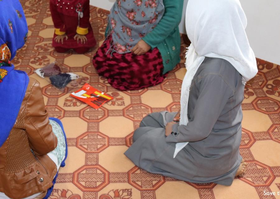 Donne di spalle riprese dall alto sono sedute a terra in circolo e indossano vestiti tradizionali afghani.