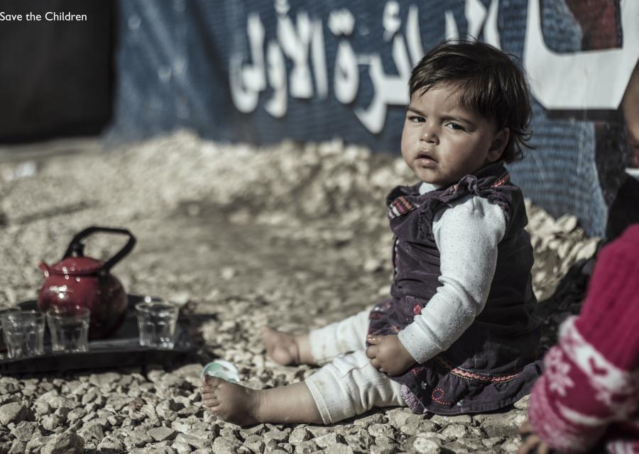 Bambina in Libano seduta per terra a piedi nudi e con lo sguardo triste