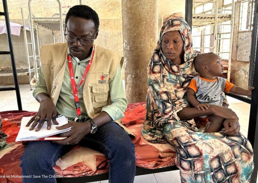 bambino in braccio a madre con accanto operatore sanitario Save the Children in Sudan 