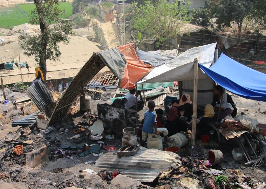 Tenda di fortuna nel mezzo di cenere e resti incendiati nel campo di coxs bazar in bangladesh. Sotto la tenda si ripara una famiglia Rohingya di varie persone 