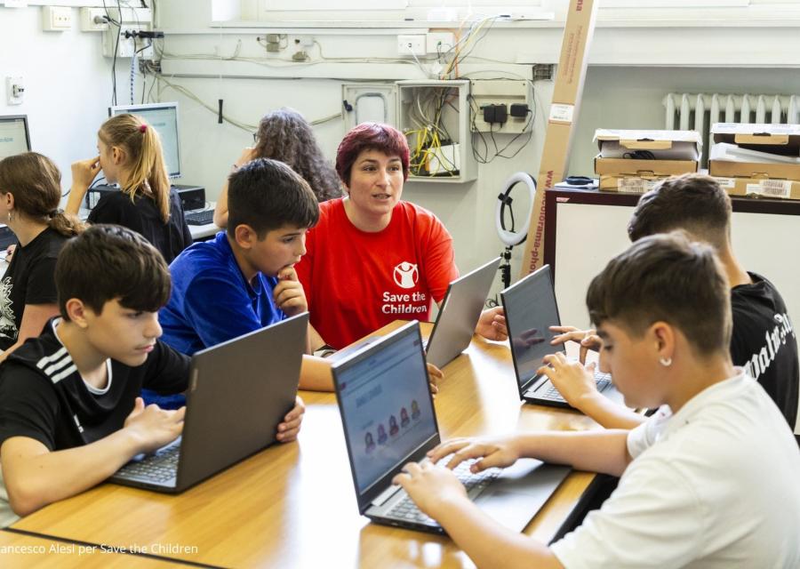 bambini che lavorano con il pc e con un operatrice save the children 