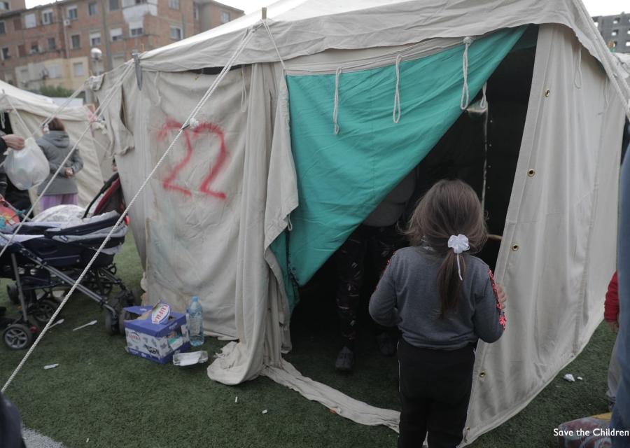 bambina di spalle di fronte a una tenda in accampamento di risposta al terremoto in Albania