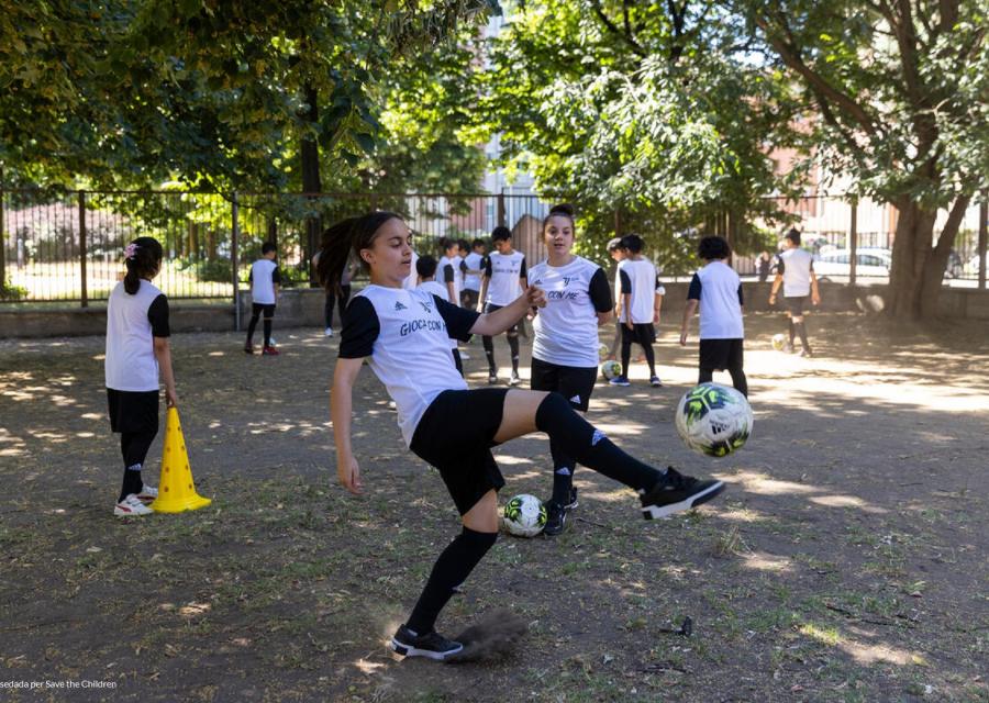 bambine che giocano a calcio ed in primo piano una di loro calcia la palla