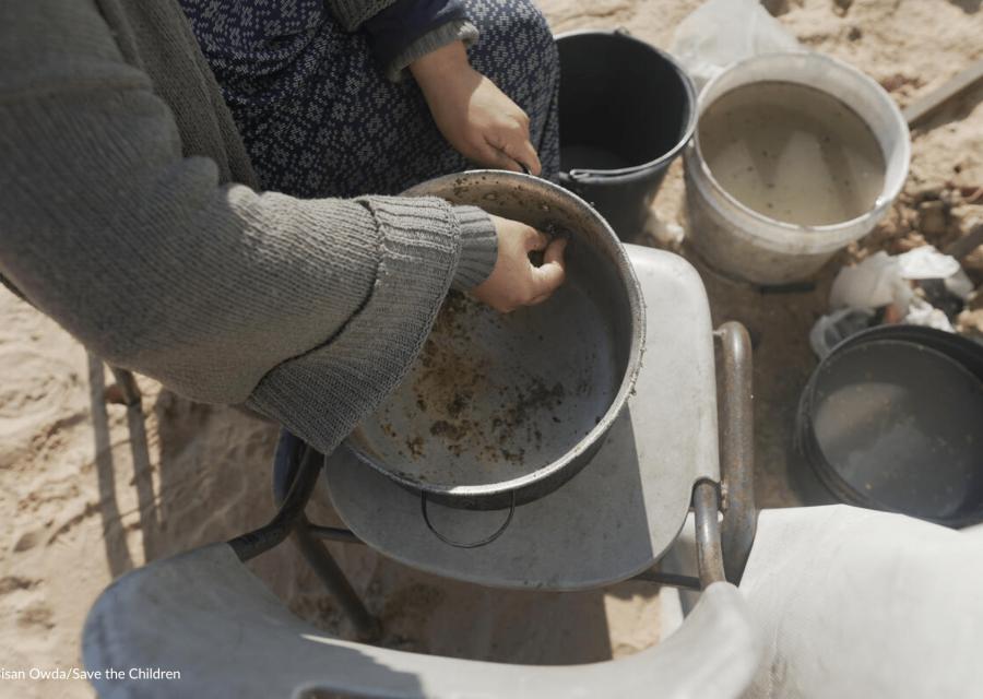 madre di gaza che raschia una pentola senza cibo 