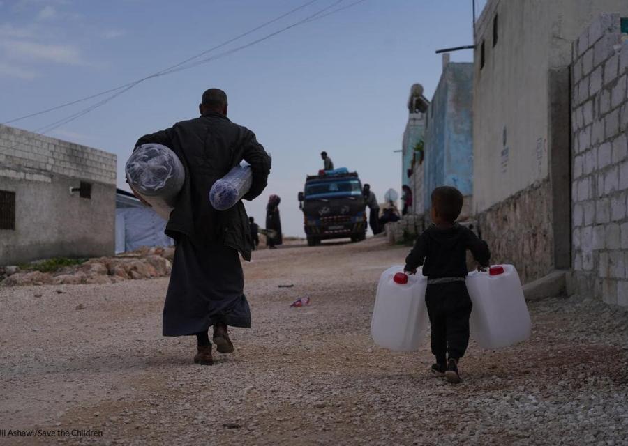 padre e bambino in Siria che trasportano taniche e sacchi dopo il terremoto che ha colpito Turchia e Siria