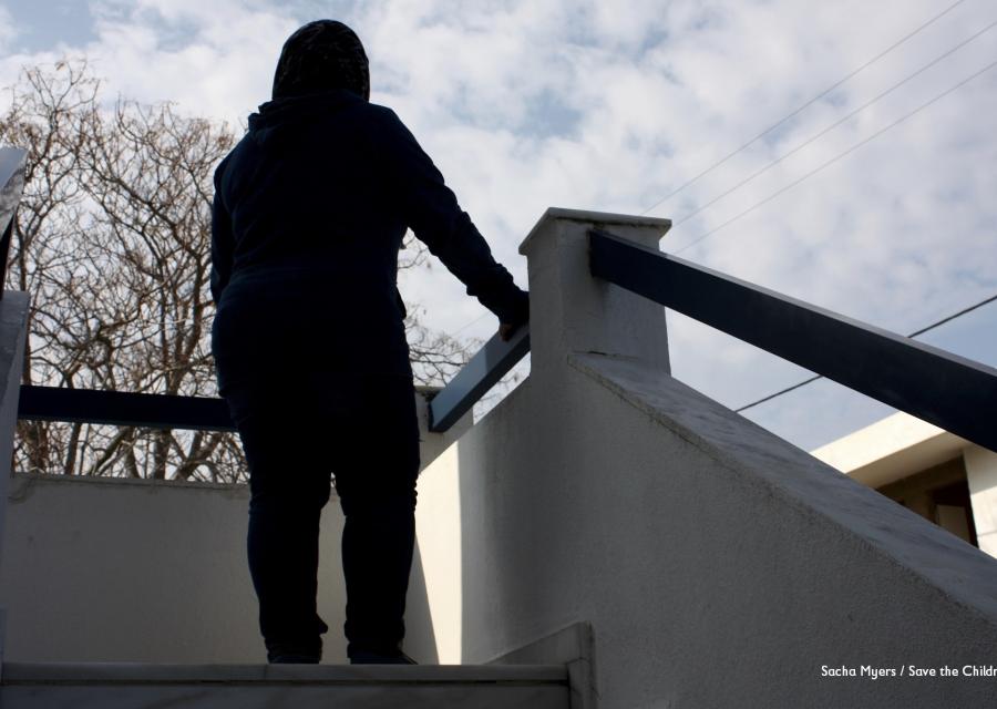Sagoma di una bambina in cima a delle scale che sta in piedi e appoggia il braccio sulla balaustra.