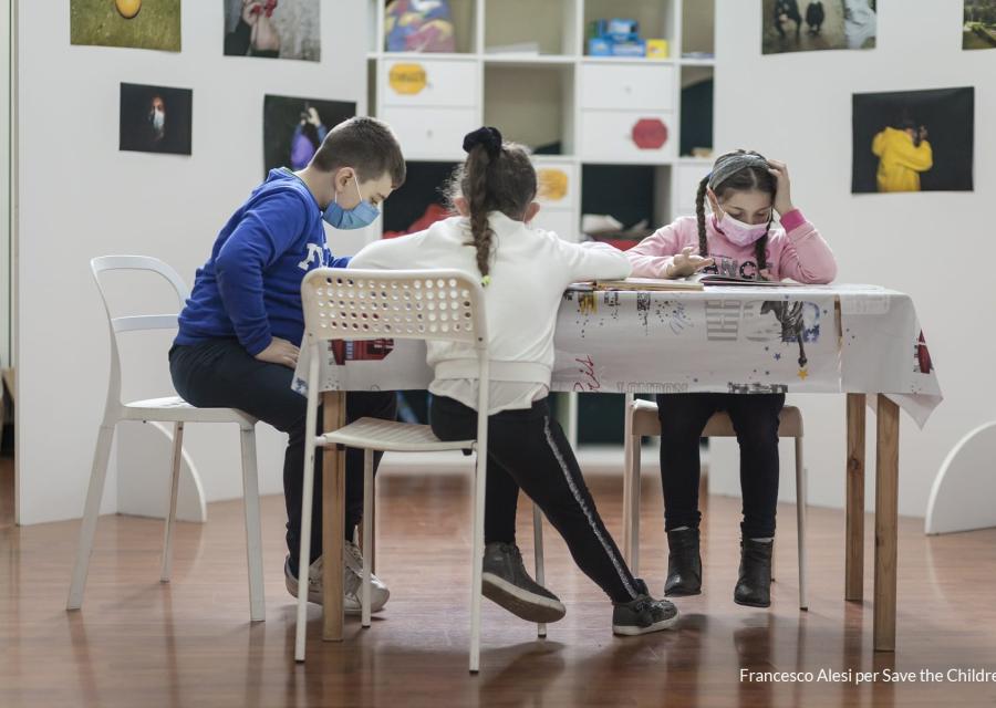 Tre bambini studiano a un tavolino