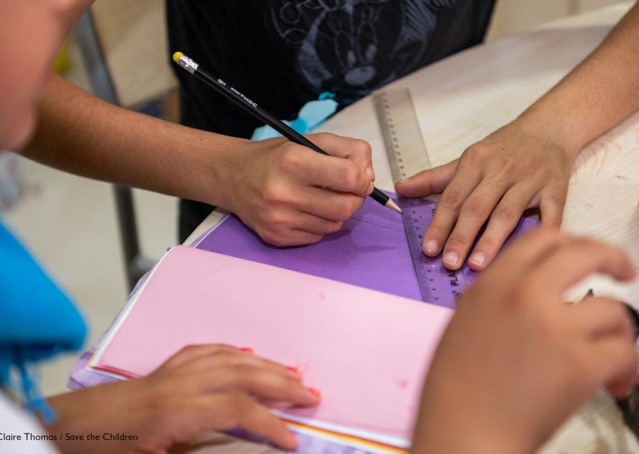 4 mani di bambini che disegnano con righello e matita su fogli