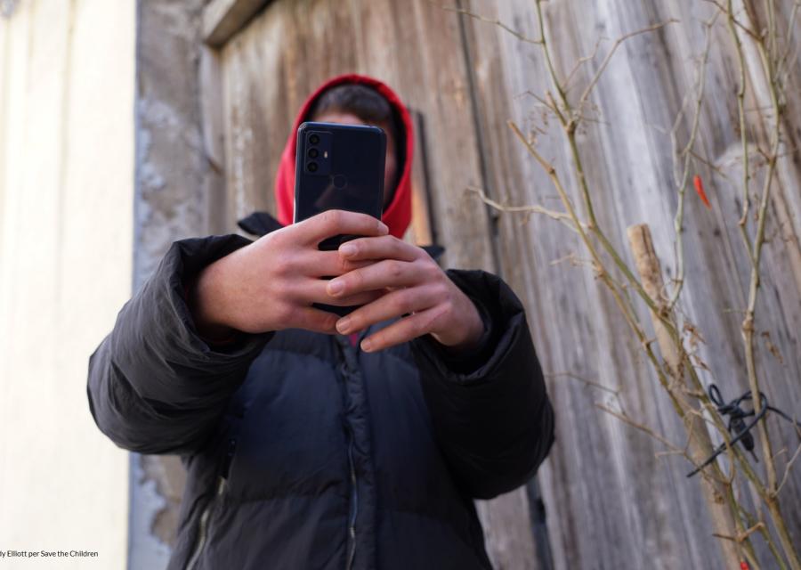 ragazzo con volto coperto dal suo cellulare che tiene in mano