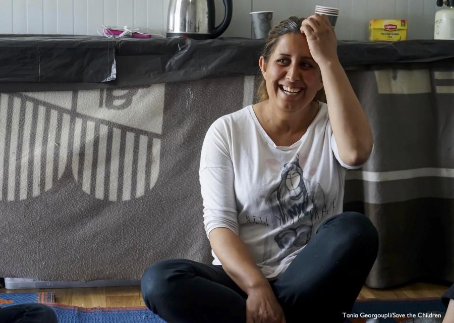 signora seduta a gambe incrociate sorridente si passa la mano fra i capelli