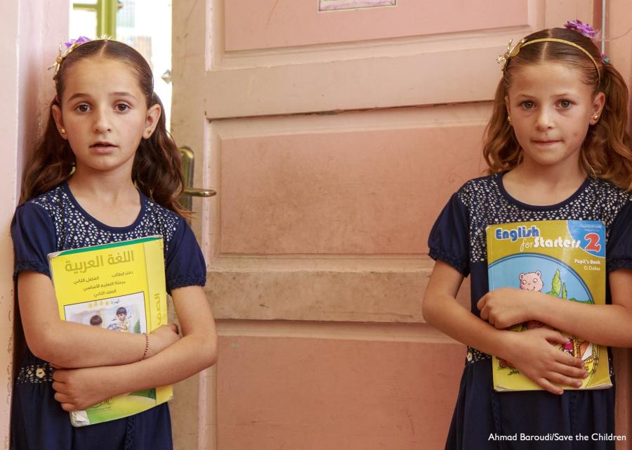due bambine bionde in piedi davanti a una porta con un libro in mano