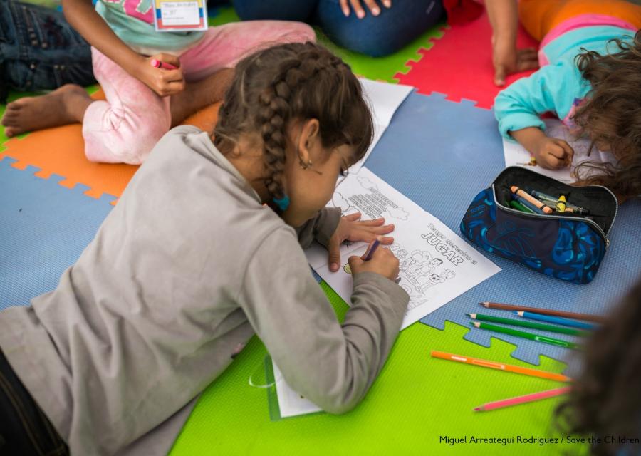 bambina sdraiata per terra su un tappeto colorato disegna