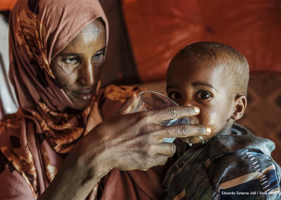 Una madre dà da mangiare a suo figlio di 5 mesi con una tazza