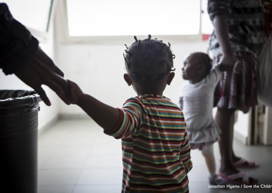 minore-migrante-di-spalle-per-mano-a-adulto