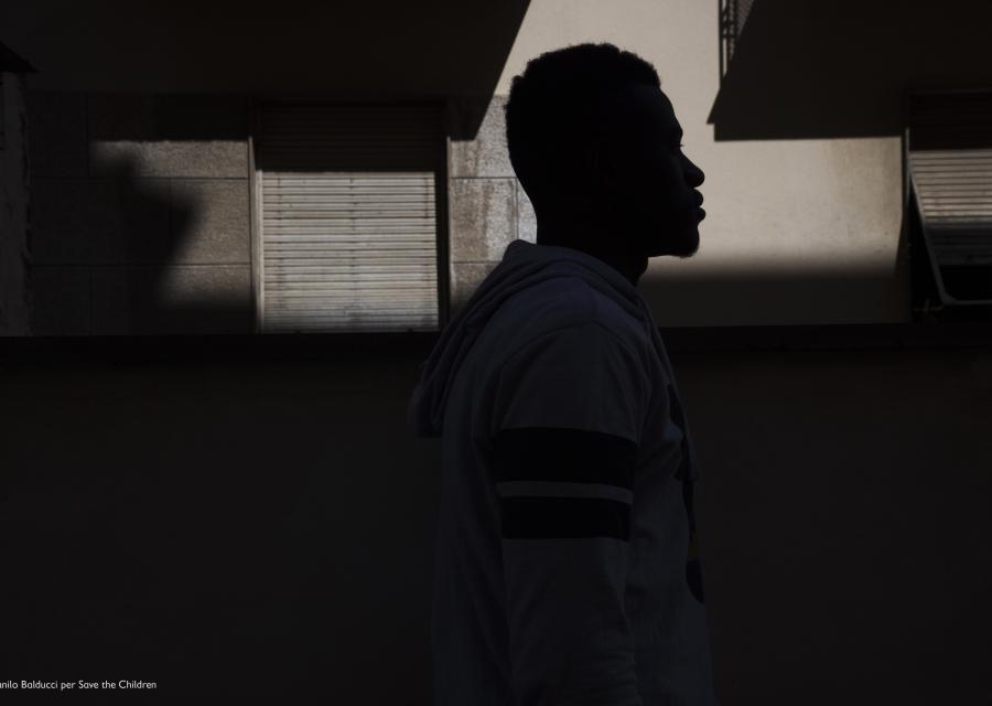 controluce di un ragazzo che cammina davanti a delle case