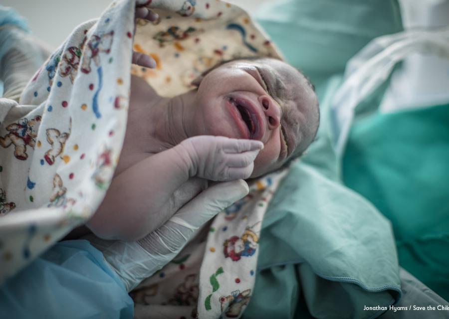 Bambino appena nato in ospedale nella mano con guanto di un medico
