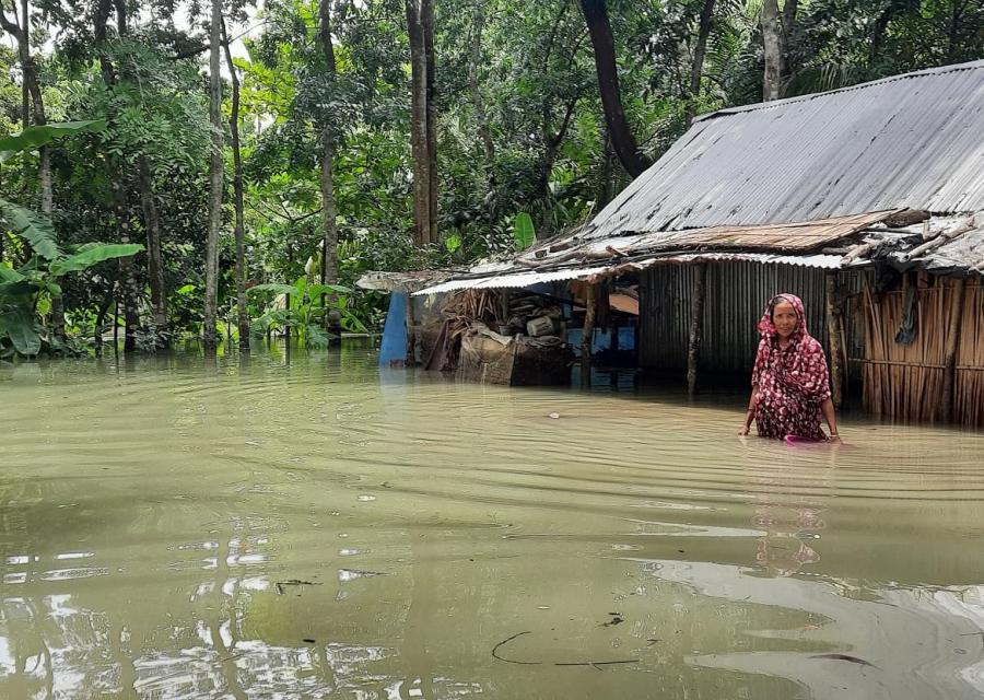 Una donna vicino alla sua capanna è immersa fino alla pancia nell acqua di un inondazione