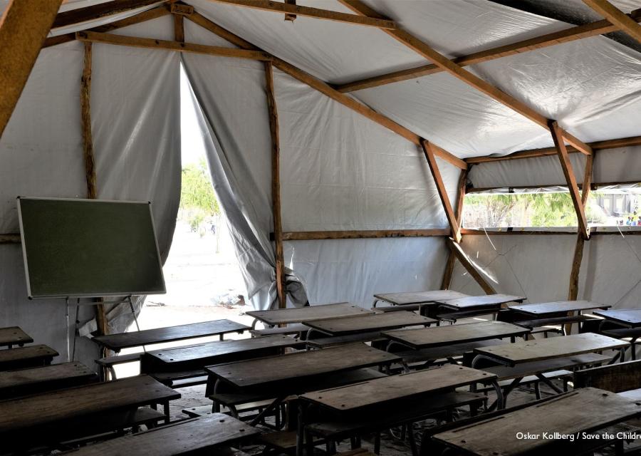 Aula con banchi di scuola e lavagna allestita in un tendone 