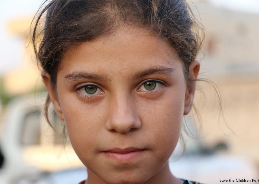 primo piano di una bambina bionda con capelli legati e occhi verdi