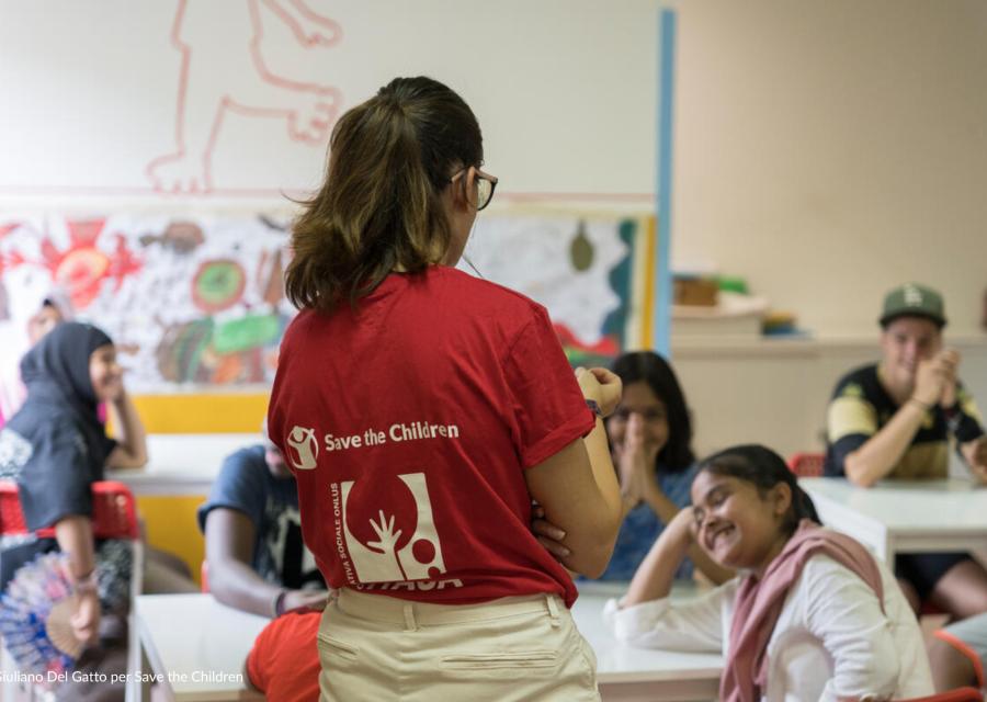 Operatrice Save the Children di spalle con bambini seduti che ridono