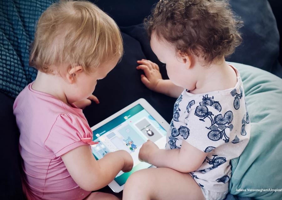 Due bambine molto piccole, una bionda e l altra castana sono sedute di spalle una di fronte all altra e tengono in mano un tablet